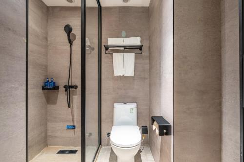 a bathroom with a toilet and a glass door at Hanting Hotel Beijing Changping Zhengfu Street in Beijing