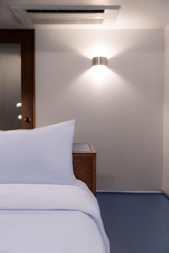 a bedroom with a white bed and a light on the wall at Small House Big Door Myeongdong in Seoul