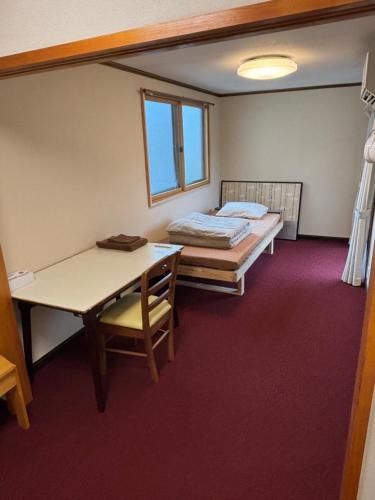 Habitación con cama, escritorio y mesa. en Popotel Three Room Z, en Matsumoto