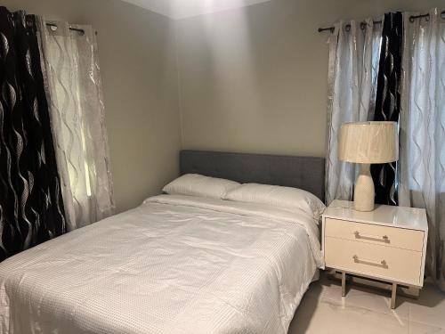 a bedroom with a white bed and a night stand at Pk cozy suite in North Miami Beach