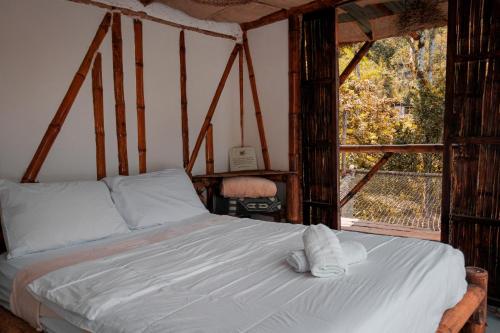 a bedroom with a bed with white sheets and a window at Victoria Ecolodge in Pereira