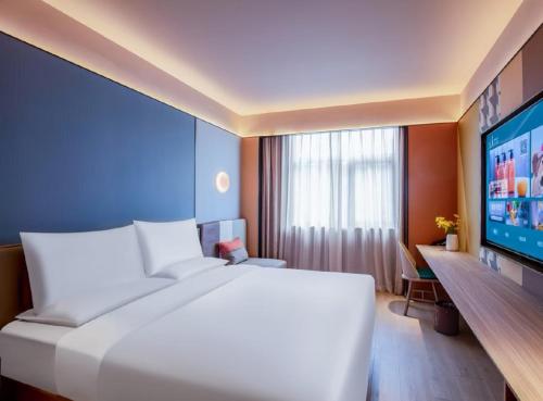 a bedroom with a large white bed and a flat screen tv at Orange Hotel Beijing Zhongguancun Xueyuan Bridge in Beijing