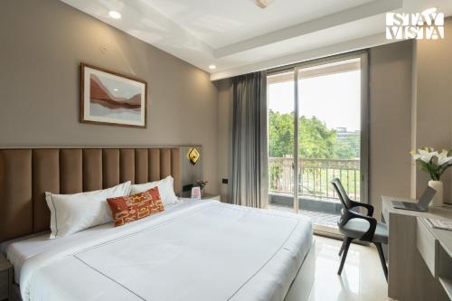 a bedroom with a bed and a desk and a window at StayVista Residences near Cyber City Hub with Gym & Air Purifier in Gurgaon