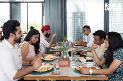 a group of people sitting at a table eating food at StayVista Residences near Cyber City Hub with Gym & Air Purifier in Gurgaon