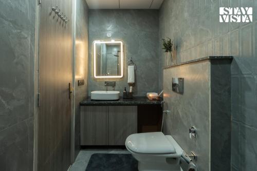 a bathroom with a toilet and a sink and a mirror at StayVista Residences near Cyber City Hub with Gym & Air Purifier in Gurgaon