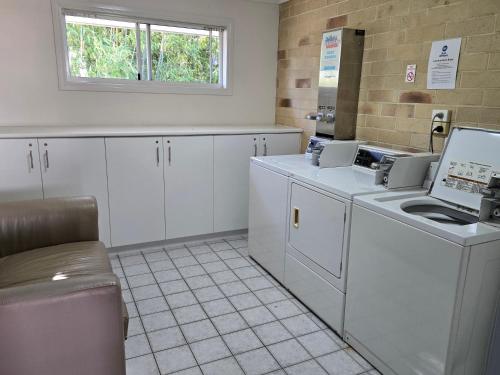 a kitchen with white cabinets and a window at Best Western Ambassador Motor Lodge in Hervey Bay