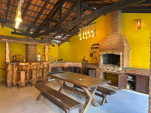 a large kitchen with a wooden table and a fireplace at Mansion SP, Heated Pool, PS5, Einstein USP in Sao Paulo