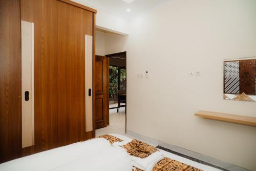 a bedroom with a bed and a wooden cabinet at Illusion Homestay in Ngaglik