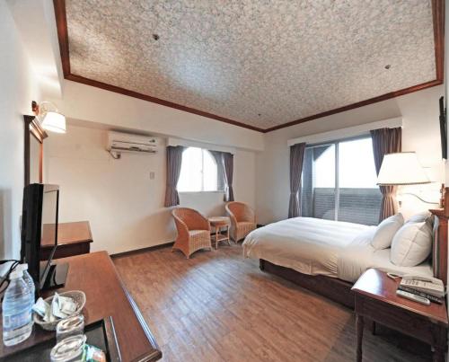 a hotel room with a bed and a desk and a tv at Kenting Holiday Hotel in Hengchun