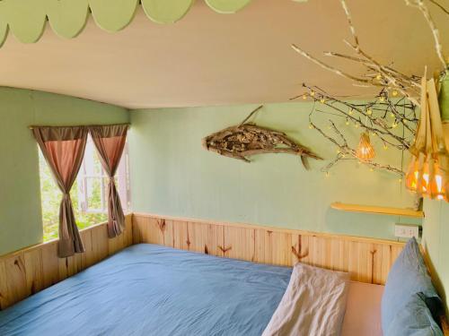 a bedroom with a bed with a fish on the wall at Cú Trên Cây Homestay in Xuan An