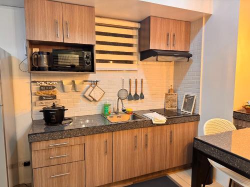 a kitchen with wooden cabinets and a sink and a microwave at RDC Cozy Suite in Tagaytay