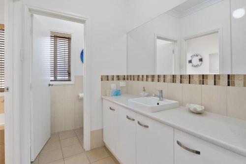 a white bathroom with a sink and a mirror at Jacks Corner - 10 Marjory Street, Normanville in Normanville