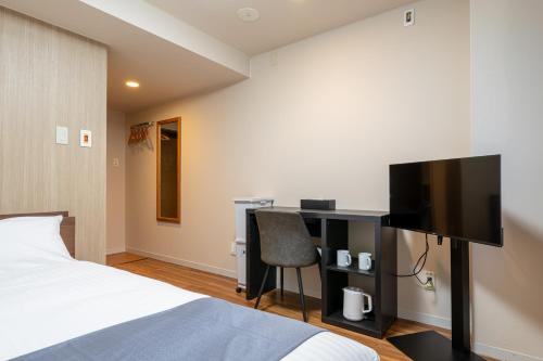 a bedroom with a bed and a desk with a television at Sleep Inn Gotanda in Tokyo
