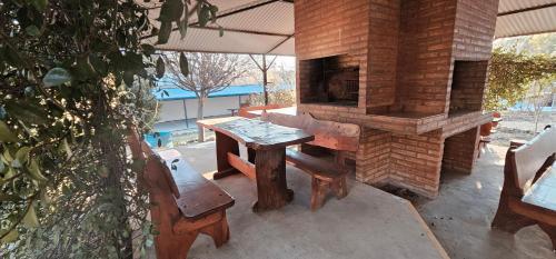 patio con mesa de madera y horno al aire libre en Hogar Lejano Cabañas y Río - Huerta Grande - Sierras de Córdoba, en Huerta Grande