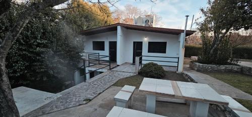 un edificio blanco con un banco delante en Hogar Lejano Cabañas y Río - Huerta Grande - Sierras de Córdoba, en Huerta Grande