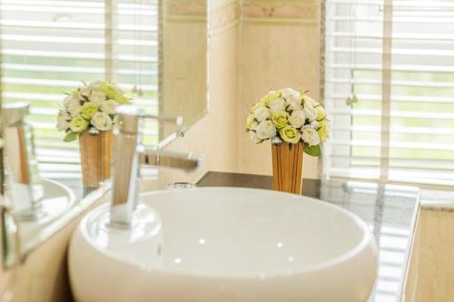 a bathroom with a sink and two vases of flowers at Tiên Hoa Sơn Villa in Da Lat