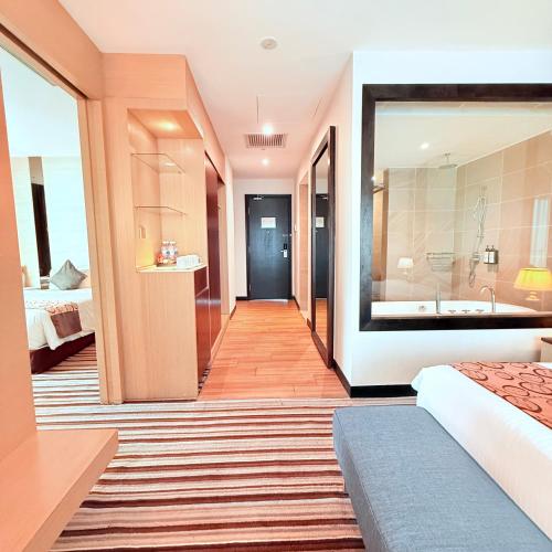 a bedroom with a bed and a bathroom with a tub at The Pure Hotel Langkawi in Kuah