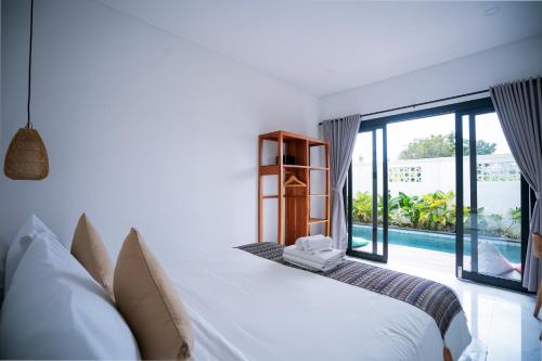 a bedroom with a bed and a large window at Serenity Uluwatu in Uluwatu