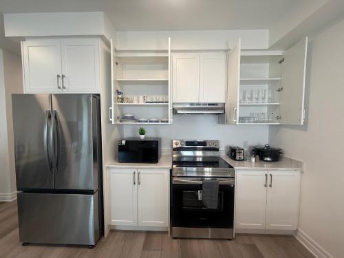 a kitchen with white cabinets and a stainless steel refrigerator at Upscale Niagara Falls Getaway - BRAND NEW in Niagara Falls