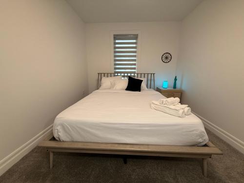 a bedroom with a bed with white sheets and a clock at Upscale Niagara Falls Getaway - BRAND NEW in Niagara Falls