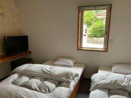 a room with two beds and a television and a window at Business Hotel Tsuwano in Tsuwano