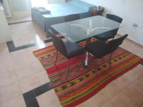 a glass table and four chairs on a rug at Todo cerca en la ciudad in Buenos Aires