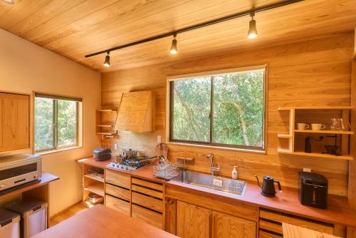 a kitchen with wooden walls and a sink and a window at 日照雨 SOBAE Stream Villa YAKUSHIMA Private villa on the river in the primeval forest in Yudomari