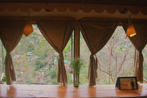 a window with a plant in a vase on a table at Cú Trên Cây Homestay in Xuan An