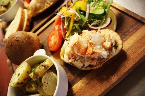 a wooden tray with a sandwich and a salad and chips at The Ram at Tivetshall in Tivetshall Saint Margaret
