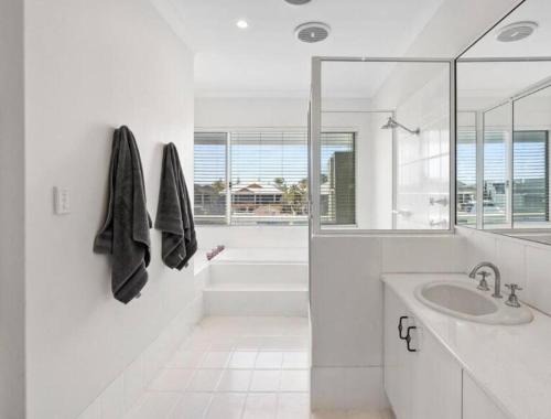 a white bathroom with a sink and a shower at Port Sails Escape in Mandurah