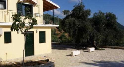 a building with a green door and a tree at Sivota Apartments in Sivota