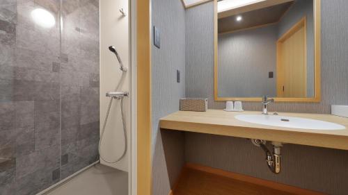 a bathroom with a sink and a shower with a mirror at かっぱの宿旅館三治郎 in Zao