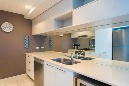 a kitchen with a sink and a refrigerator at Silvershore Apartments on the Broadwater in Gold Coast