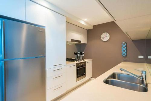 a kitchen with a stainless steel refrigerator and a sink at Silvershore Apartments on the Broadwater in Gold Coast
