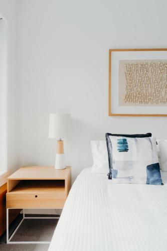 a bedroom with a bed with a nightstand and a picture at Cavvanbah Lane in Byron Bay