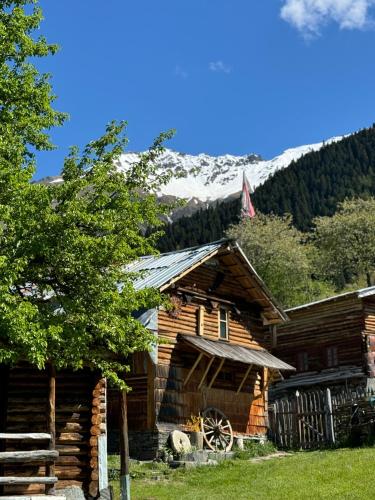 a log cabin with a snow covered mountain in the background at Ipderi cottages in Lekhtagi