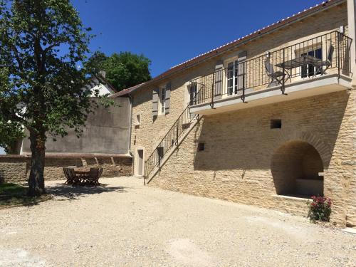 a brick building with a balcony and a bench at La Maison des Belles Filles in Pernand-Vergelesses