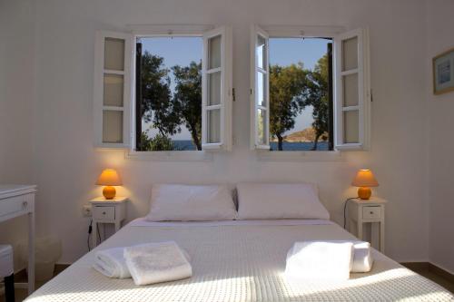 a bedroom with a white bed with two windows at Almira Suites - Seafront - Naousa Paros in Naousa
