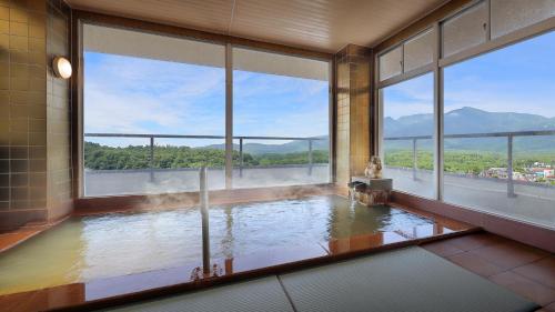 a large room with a bath tub with windows at かっぱの宿旅館三治郎 in Zao