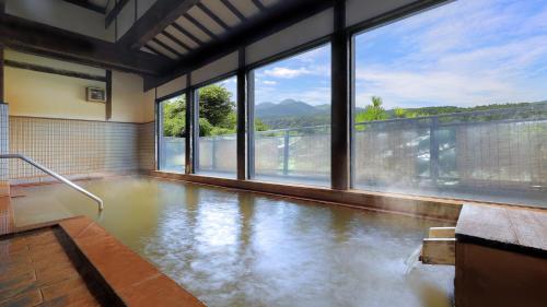 a room with a pool of water with windows at かっぱの宿旅館三治郎 in Zao
