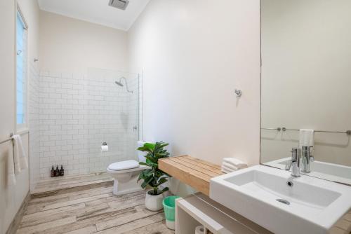 a white bathroom with a sink and a toilet at Cove Quarters in Byron Bay
