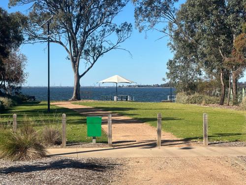 a park with a bench and an umbrella and the water at Royal Mail Hotel Mulwala in Mulwala