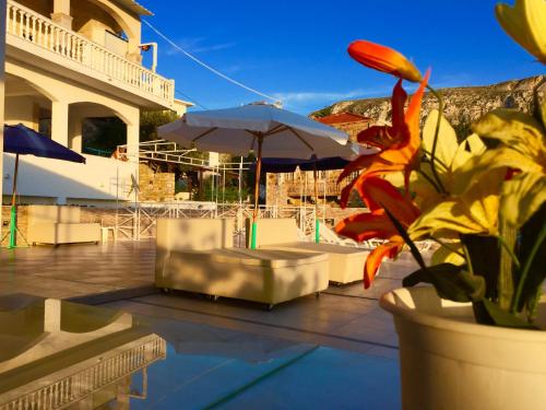 a patio with a table and umbrella and a potted plant at Alkyonis Apartments in Panormos Kalymnos