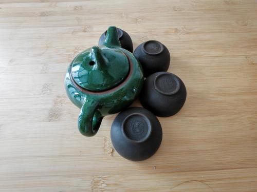 a green vase sitting on a table with four stones at Qingdao Linlin Tranquil Residence in Qingdao