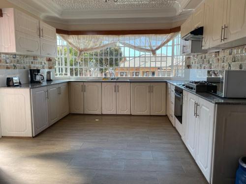 a large kitchen with white cabinets and a large window at Cozy home in Area 43, Lilongwe in Lilongwe