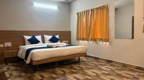 a bedroom with a bed with blue pillows and a window at Ponneri Gymkhana Club in Ponneri