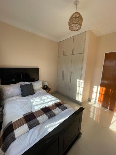 a bedroom with a large bed with a checkered blanket at Cozy home in Area 43, Lilongwe in Lilongwe