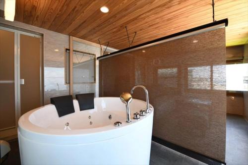 a white tub in a room with a glass wall at BU1 瀬々串 海テラスSesekushi Umi terrace in Kagoshima