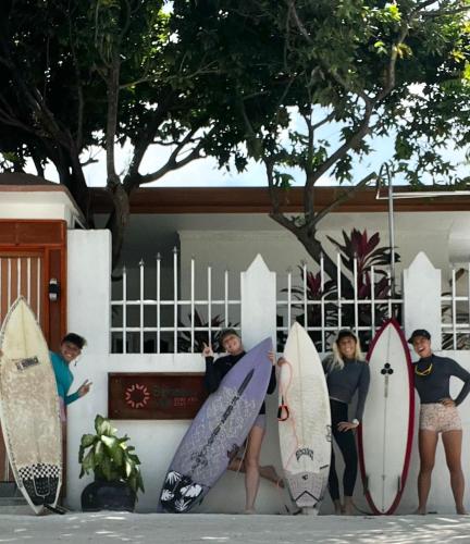 a group of people standing next to a fence with their surfboards at Bahaaru Villa Surf and Stay in Himmafushi