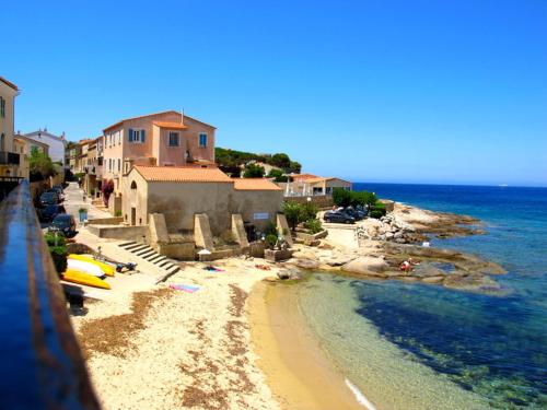 a view of a beach with buildings and the ocean at Hotel de la Plage Santa Vittoria in Algajola